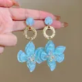 Detailed view of bohemian light blue resin flower drop earrings with iridescent beads - Blue
