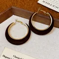 Close-up detail of brown flocked hoop earrings with elegant gold metal lining. - Brown
