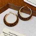 Close-up detail of vintage leopard print flocking hoop earrings with a gold metal finish. - Leopard Coffee