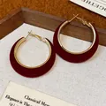 Macro detail of elegant red velvet flocked hoop earrings with gold-toned metal accents - Red