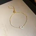 Premium detail of a gold-toned adjustable heart tennis bracelet with shimmering zircon stones - Bracelet / Gold