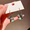 Close-up of Bohemian zircon and green stone bead dangle earrings held on a white card - Hook Style / Silver, Green