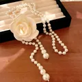 Elegant long pearl necklace with large rose flower detail on a classic jewelry tray - White