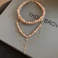 Macro view of French vintage layered pearl necklace featuring exquisite diamond cross pendants - Gold Brown