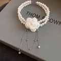 Detail view of a double-layer pearl choker with a delicate white knitted flower - White