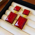 Close-up of vintage geometric red earrings with gold frames in a display box. - Gold-Red