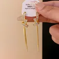 Eleganti orecchini a nodo dorati con nappe in zircone scintillante e perni in argento. - Placcato Oro Vero / Oro