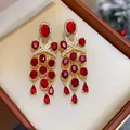 Gros plan de boucles d'oreilles vintage avec pompons en zircon rouge dans un écrin - Style Long à Gland (WE5589) / Or Rouge