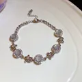 Macro detail of elegant silver zircon chalcedony flower bracelet displayed on white ceramic - Silver