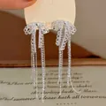Primo piano di eleganti orecchini a fiocco con strass scintillanti in finitura argento - Nappina a Fiocco / Argento