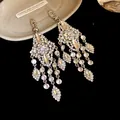 Close-up of luxury silver needle earrings with shimmering waterdrop rhinestone tassels - Rhombus Tassel Style / Silver