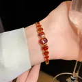 Elegant gold plated bracelet with oval orange zircon stones worn by a female model - Oval Red Zirconia Geometric Style (128#)