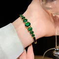 Elegant gold-plated bangle featuring oval emerald green zircons on a lady's wrist. - Gradient Oval Zirconia Style (130#)