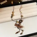 Close-up of Bohemian necklace with wooden beads and ceramic pendant in jewelry box. - Necklace-Coffee
