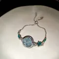 Close-up of elegant silver star bracelet watch with light blue dial and green stones - Star Bracelet Watch / Silver-Green