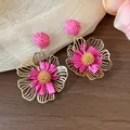 Detailansicht von rosa Raffia-Blumenohrringen mit goldenen Metallblütenblättern, Urlaubsstil - Blumen-Stil / Fuchsia