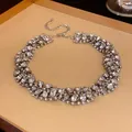 Close-up of a sparkling rhinestone twisted collar necklace on a display tray. - Twisted Twist Necklace / Silver