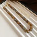 Détail du collier de perles marbrées avec des tourbillons ambre et gris élégant - Style Lavis d'Encre Marbre / Gris