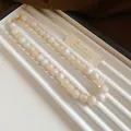 Vue détaillée des perles de marbre crème élégantes sur un collier de clavicule chic - Style Lavis d'Encre Marbre / Blanc