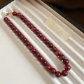 Détail d'un collier de perles rouges marbrées élégantes avec un fermoir doré rétro - Style Lavis d'Encre Marbre / Rose rouge