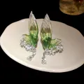 Close-up showing the detail of green fairy wing ear clips with sparkling crystal flowers. - Ear Cuff (Silver-Green)
