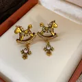 Detailed view of vintage gold rocking horse earrings with cross pendants and zircons. - Rocking Horse Cross Stud Earrings (WE5467) / Gold