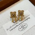 Close-up detail of cute flocked teddy bear earrings with pearls and 18K gold plating. - Pearl Bear (Gold Plated) / Gold/Coffee (7#)
