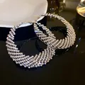 Primer plano detallado de aretes de aro grandes plateados con pedrería brillante - Pendientes Geométricos Luna / Plateado