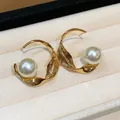 Primer plano de elegantes pendientes de aro metálicos dorados con perlas blancas - Dorado