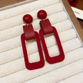 Close-up of retro red rectangular geometric drop earrings with unique textures and silver needles - Silver Earring Post Style / Red