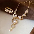 Close-up of vintage style gold necklace and earring set with oval pearls on textured fabric. - Gold-White Spiral Style