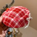 Primo piano di un fermaglio natalizio a quadri rossi con un delicato fiocco di perle. - Stile Fiocco Perla Quadretti Rosso (1)
