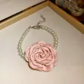 Detail einer französischen rosa Stoffrose und Perlenkette in einer Schmuckschale - Armband / Rosa