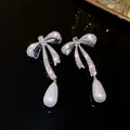 Elegant silver-tone crystal bow earrings with white teardrop pearl drop pendants - Bowknot Drop Pearl Style