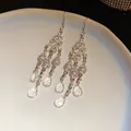 Detailed view of hollow rhinestone tassel earrings with crystal water drop charms. - Silver