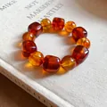 Close-up of amber acrylic beaded bracelet with irregular geometric shapes on a book. - Dark Coffee