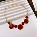 Detailed view of the irregular red enamel circular pendants on a gold chain. - Necklace / Red