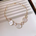 Detailed view of irregular marbled circular pendants on a gold chain necklace. - Necklace / White