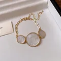 Detailed view of minimalist gold-tone necklace with three pearlescent circular charms. - Bracelet / White