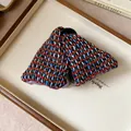 Detailed view of a woven plaid fabric triangular shark hair clip with vibrant color patterns. - Hair Claw / Red & Blue