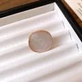 Detailed macro view of a vintage gold ring featuring a round pearlescent resin face inlay - Ring / White