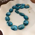 Macro view of a vintage blue oval resin bead necklace displayed on a white plate - Necklace (HN7899) / Gold-Green