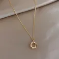 Detalle macro de un colgante de dos anillos entrelazados en oro con cristales en raso - Estilo Ovalado Geométrico de Diamantes de Imitación Dorados (45#)