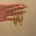 Vista dettagliata di eleganti orecchini lunghi dorati con nappe e ciondoli a forma di foglia - Nappina Oro (1#)