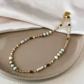 Detail view of a Baroque pearl and stone cylinder beaded necklace on a beige tray - Multicolor Stone Style