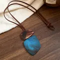 Detailed view of irregular blue and brown marbled resin pendant necklace on a wooden surface. - Necklace Style 1 (WN1631)