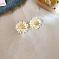 Close-up of white floral stud earrings with gold centers on textured paper. - 28# Silver Pin-White