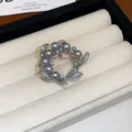 Gros plan d'une élégante broche couronne avec perles grises et zircons dans un écrin - 4# Style Couronne Argentée