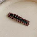 Detailed view of a black rectangular hair clip embellished with sparkling pink rhinestones. - Light Purple
