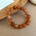 Macro view of a retro amber smudged beaded bracelet on a natural wooden surface texture - Bracelet / Brown